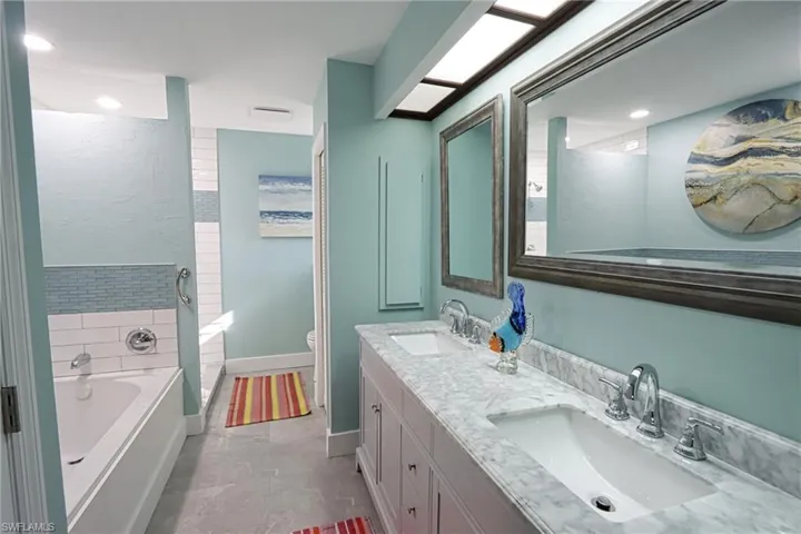 Bathroom with vanity with extensive cabinet space, dual sinks, toilet, tile floors, and a bathtub