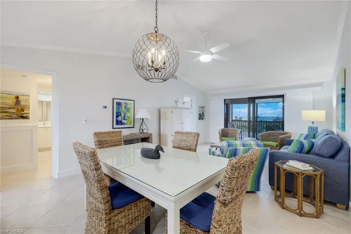 Dining room featuring ceiling fan with notable chandelier, lofted ceiling, and light tile patterned flooring