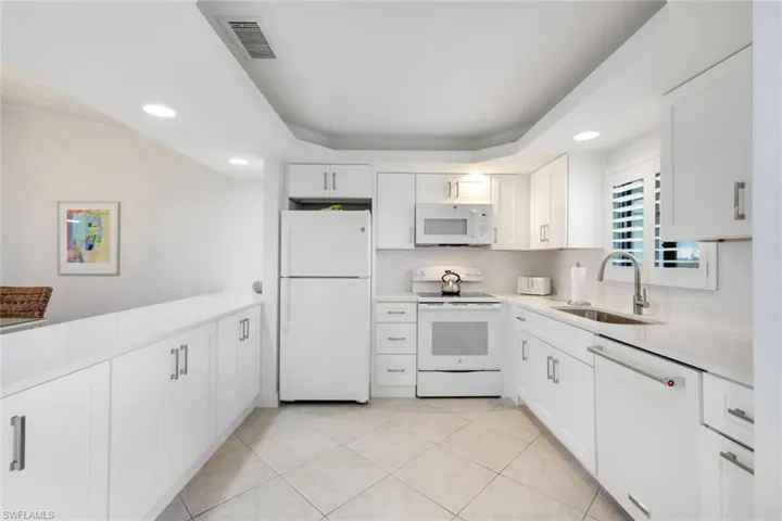 Kitchen featuring white cabinets, white appliances, sink, and light tile patterned floors