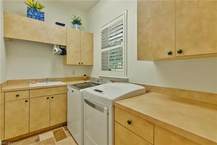 Washroom with cabinets, separate washer and dryer, and sink