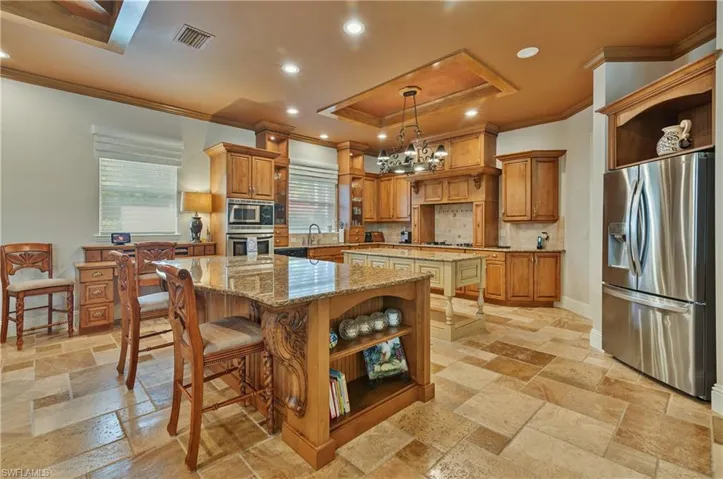 Kitchen featuring appliances with stainless steel finishes, hanging light fixtures, tasteful backsplash, a kitchen island, and crown molding