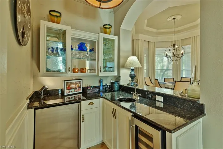 Kitchen featuring hanging light fixtures, dark stone countertops, white cabinetry, and wine cooler