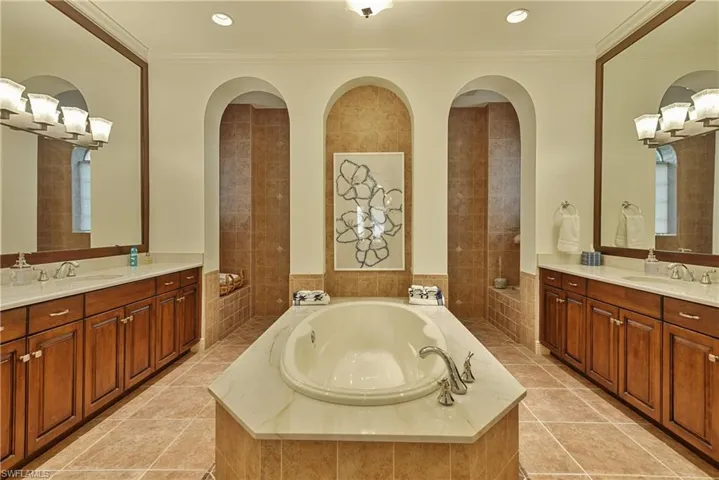 Bathroom featuring ornamental molding, tile patterned floors, tiled tub, and vanity