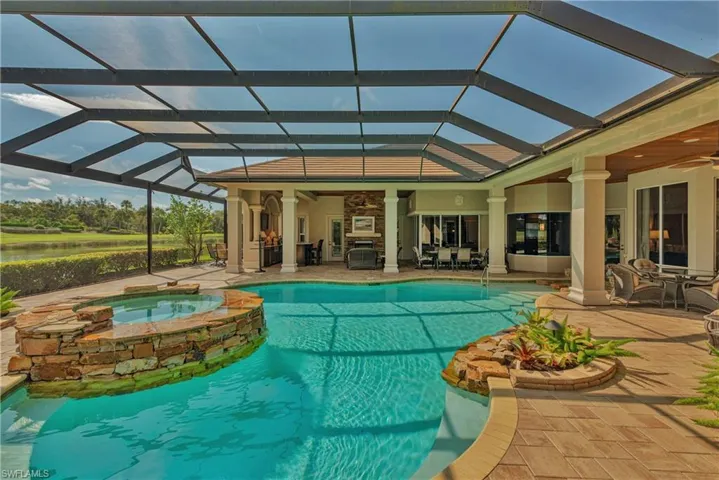 View of swimming pool with a patio, glass enclosure, ceiling fan, and an in ground hot tub