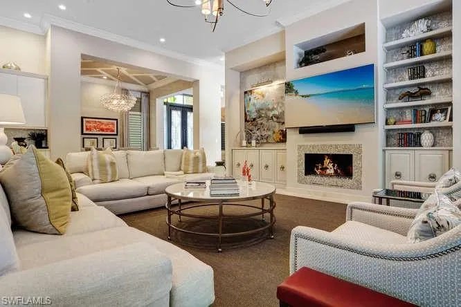 Carpeted living room featuring a notable chandelier, built in shelves, and ornamental molding