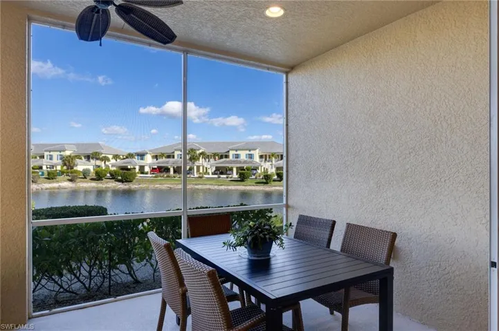 Screened porch featuring a textured wall, a water view, a textured ceiling, floor to ceiling windows, and a residential view
