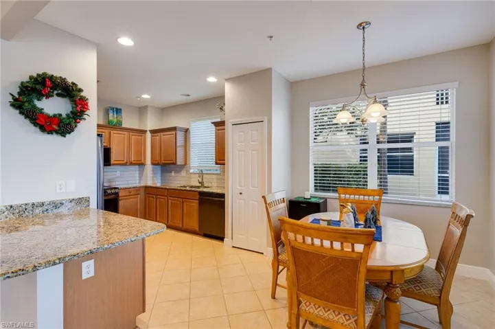 Kitchen featuring backsplash, light stone counters, hanging light fixtures, light tile patterned floors, and dishwasher
