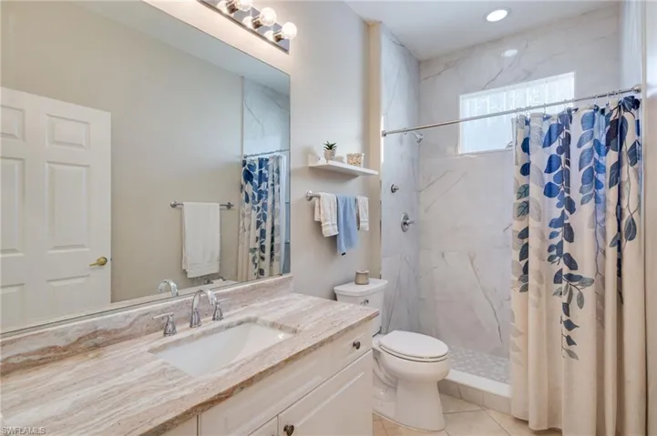 Bathroom with vanity, a marble finish shower, and light tile patterned flooring