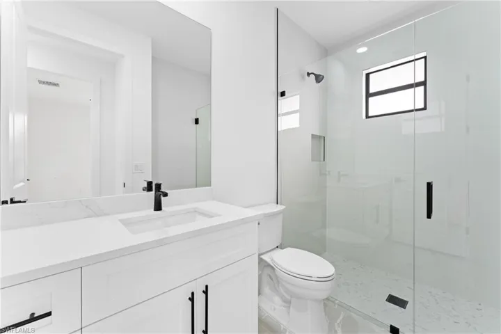Bathroom featuring walk in shower, vanity, and toilet