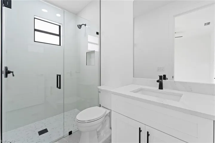 Bathroom featuring an enclosed shower, vanity, and toilet