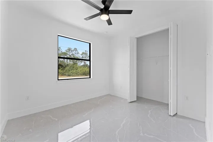 Unfurnished bedroom with ceiling fan and a closet
