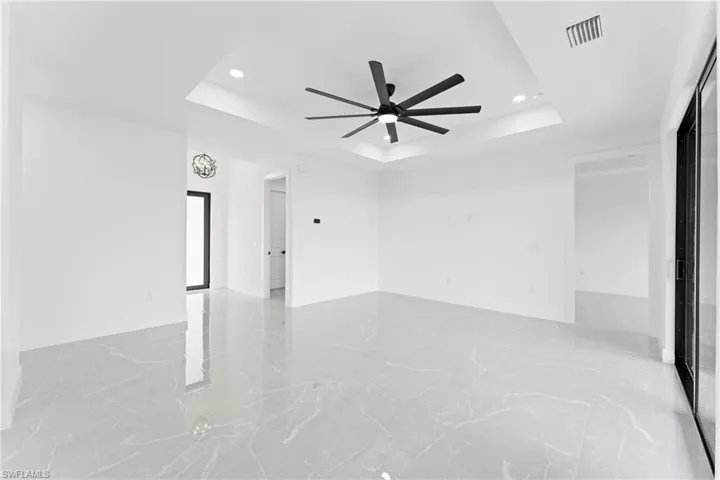 Unfurnished room featuring a raised ceiling and ceiling fan