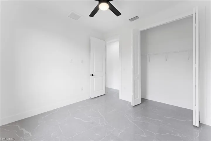 Unfurnished bedroom with ceiling fan and a closet