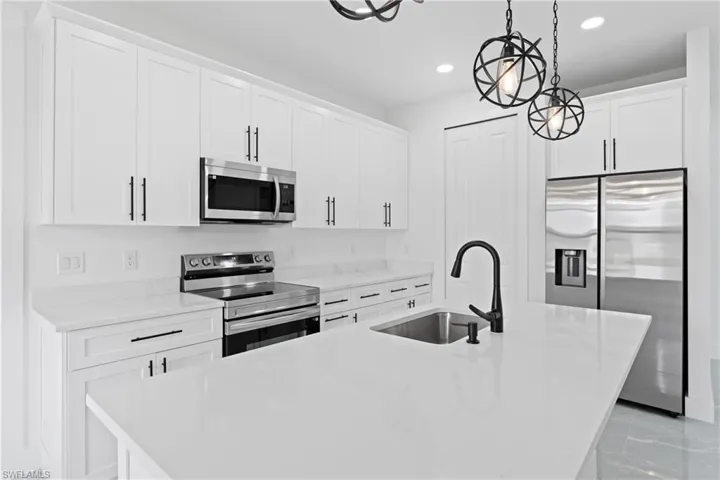 Kitchen with pendant lighting, sink, stainless steel appliances, and a center island with sink