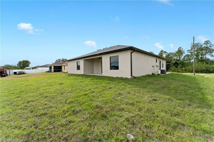 View of property exterior with a lawn and central AC unit
