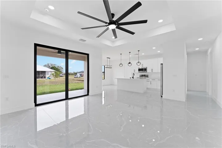 Unfurnished living room featuring a raised ceiling, ceiling fan, and sink