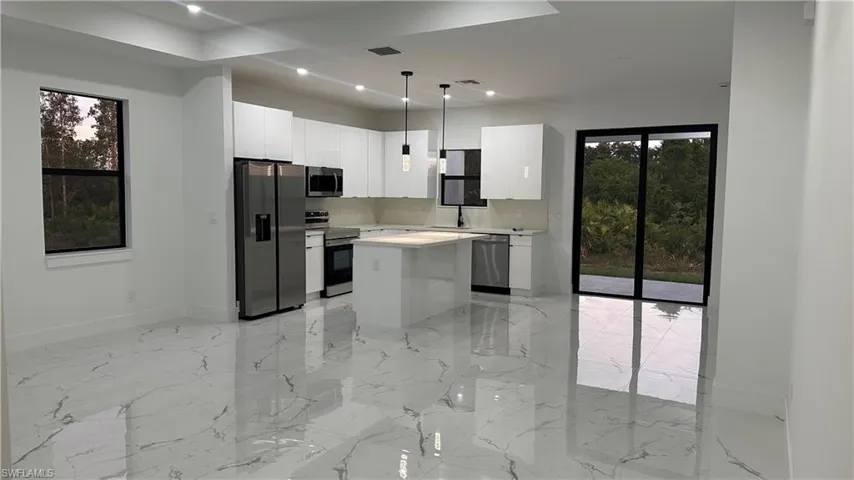 Kitchen featuring a center island, decorative light fixtures, white cabinetry, and stainless steel appliances
