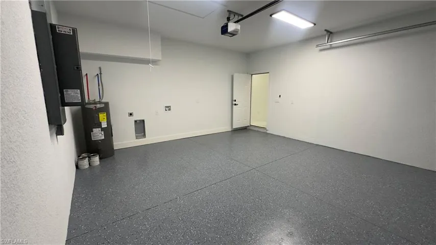 Garage featuring a garage door opener and electric water heater