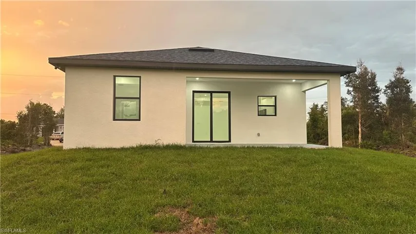 Back house at dusk with a lawn