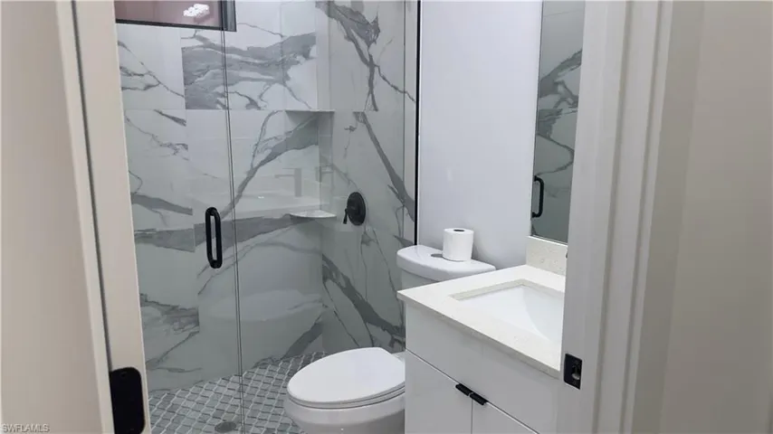 Bathroom with an enclosed shower, vanity, and toilet