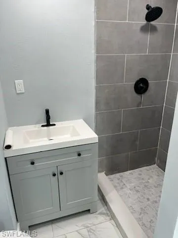 Bathroom featuring a tile shower, vanity, and toilet