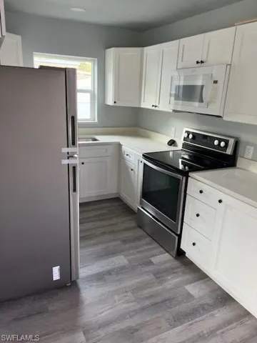 Kitchen with light wood-type flooring, white cabinetry, and appliances with stainless steel finishes