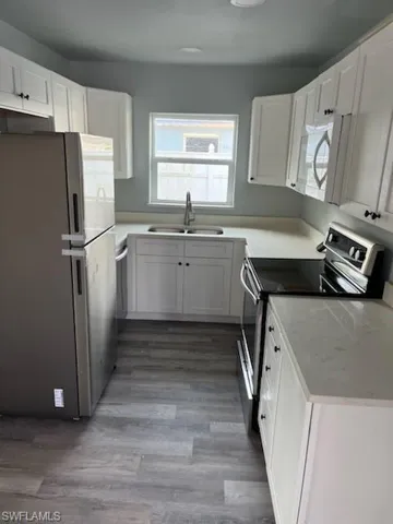 Kitchen featuring sink, white cabinets, and appliances with stainless steel finishes