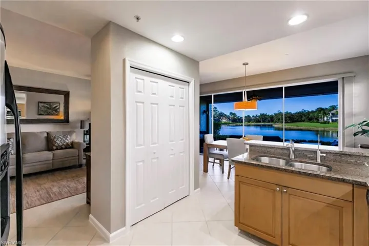 Kitchen featuring pendant lighting, dark stone counters, a water view, sink, and light tile patterned floors