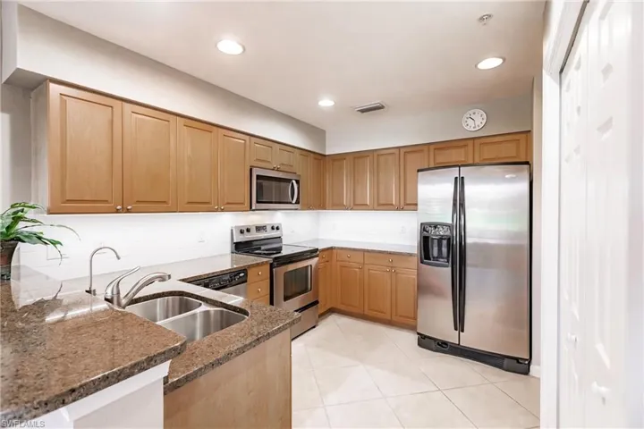 Kitchen featuring kitchen peninsula, dark stone countertops, stainless steel appliances, and sink