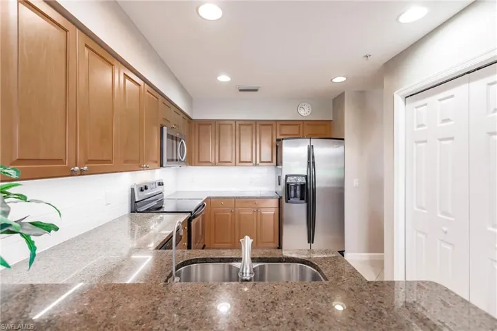 Kitchen featuring appliances with stainless steel finishes, backsplash, light stone counters, and sink