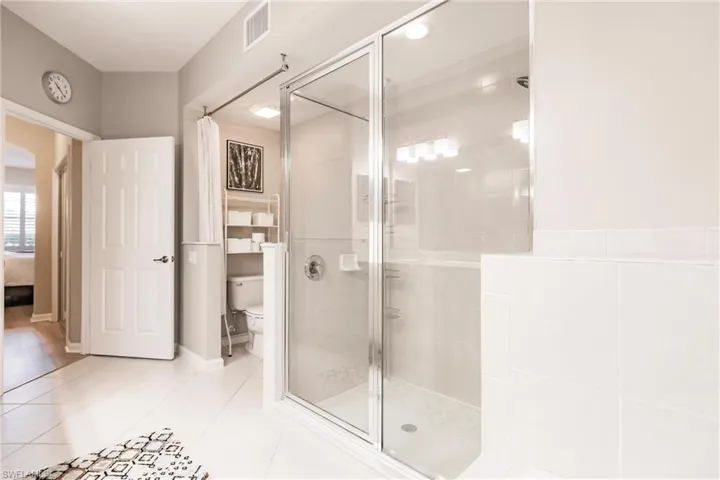 Bathroom featuring tile patterned flooring, toilet, and walk in shower