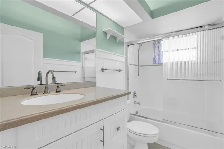 Full bathroom featuring vanity, shower / bath combination with glass door, and toilet