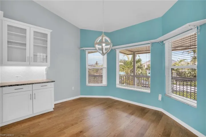 Unfurnished dining area with a chandelier, hardwood / wood-style flooring, and a wealth of natural light