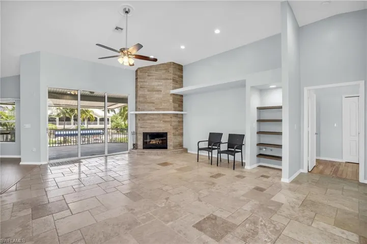Unfurnished living room with a high ceiling, a fireplace, ceiling fan, and light hardwood / wood-style floors