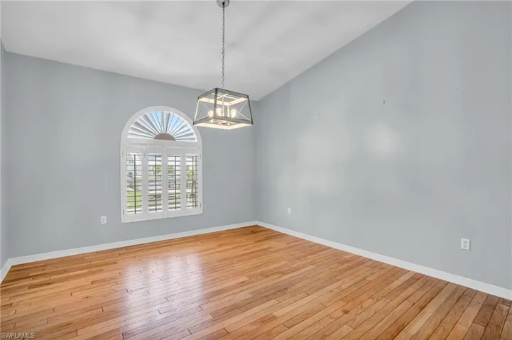 Spare room with light hardwood / wood-style floors and a notable chandelier