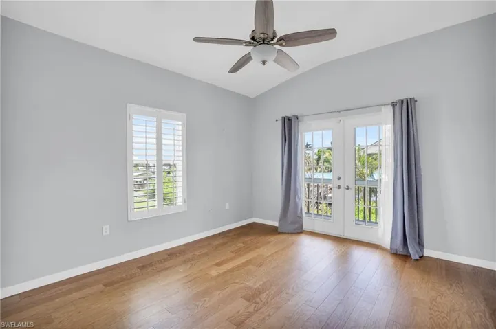 Unfurnished room with hardwood / wood-style flooring, lofted ceiling, french doors, and ceiling fan