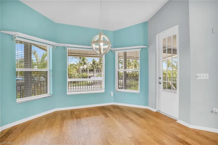 Unfurnished dining area featuring a healthy amount of sunlight, light wood-type flooring, and an inviting chandelier