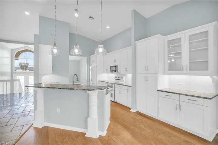 Kitchen featuring light hardwood / wood-style floors, tasteful backsplash, white cabinets, and stone countertops