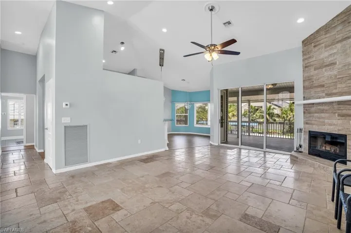 Unfurnished living room with a large fireplace, a wealth of natural light, ceiling fan, and high vaulted ceiling