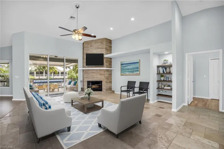 *Virtually Staged* Living room featuring light wood-type flooring, ceiling fan, a large fireplace, and a towering ceiling