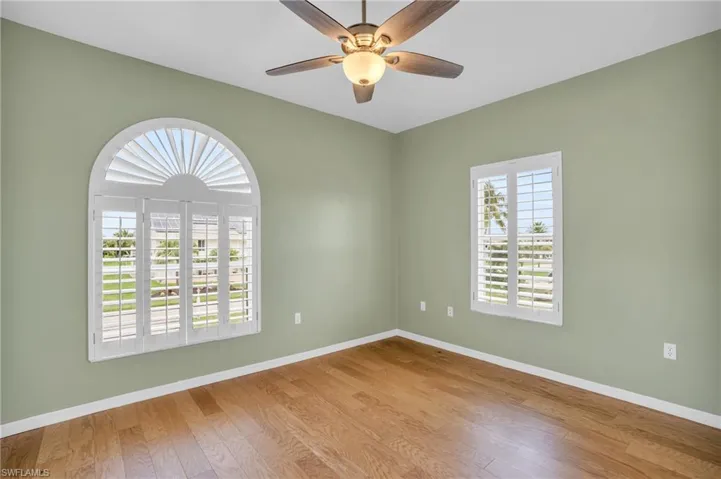 Spare room with hardwood / wood-style floors, ceiling fan, and plenty of natural light