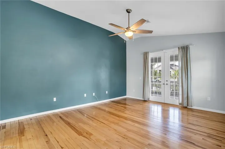 Empty room with lofted ceiling, french doors, light hardwood / wood-style flooring, and ceiling fan