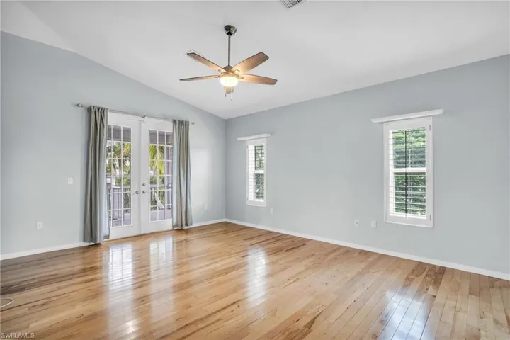Spare room featuring lofted ceiling, french doors, light wood-type flooring, and ceiling fan