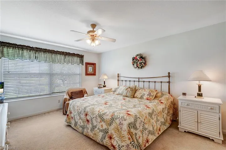 Bedroom with light carpet, baseboards, and a ceiling fan