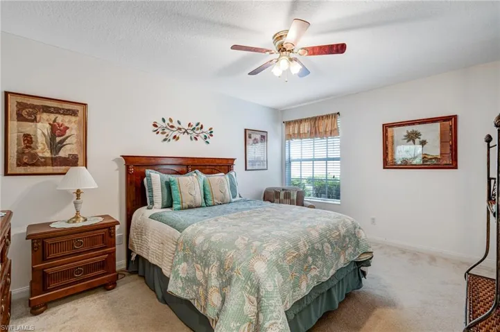 Bedroom featuring light colored carpet, ceiling fan, and baseboards