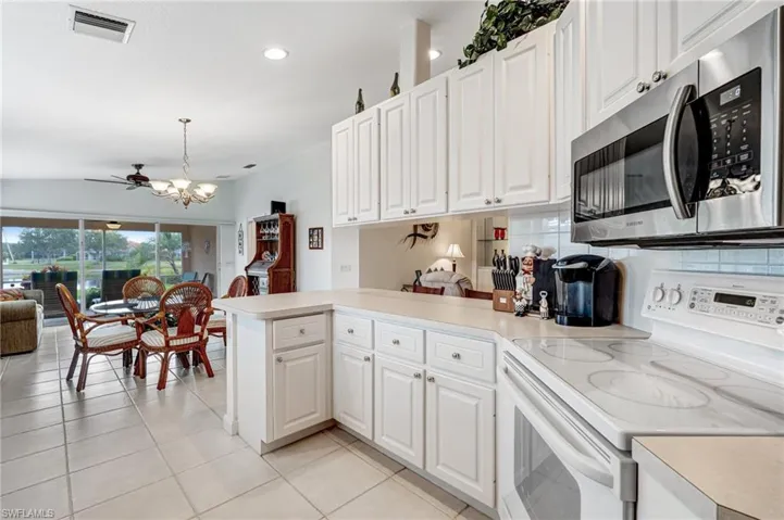 Kitchen featuring stainless steel microwave, white electric range oven, a peninsula, light countertops, and open floor plan