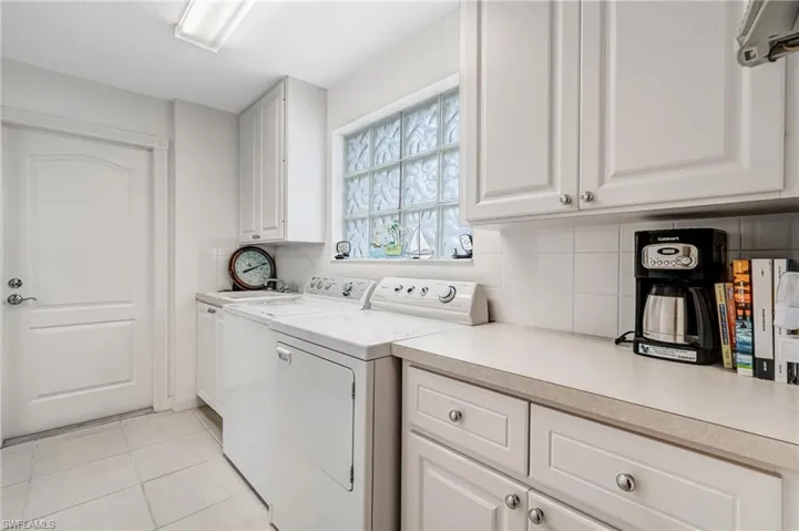 Washroom with cabinet space, independent washer and dryer, and light tile patterned floors