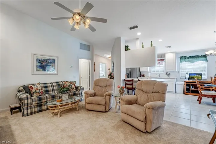 Living area featuring vaulted ceiling, ceiling fan, recessed lighting, a chandelier, and light colored carpet