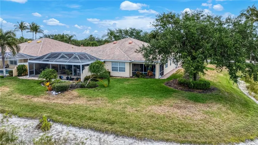 Rear view of property with a lawn, a lanai, a tiled roof, stucco siding, and a patio area