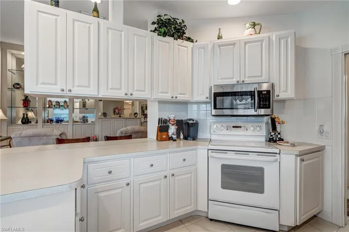 Kitchen featuring stainless steel microwave, electric range, white cabinets, a peninsula, and recessed lighting